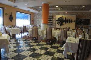 Un comedor con mesas y sillas blancas. en Hotel Puerto de Las Nieves, en Agaete