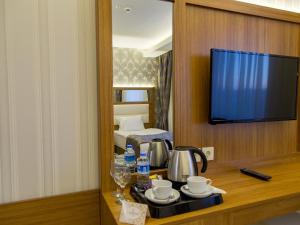 um quarto com uma televisão e uma mesa com um conjunto de chá em Carmine Otel em Kırıkkale