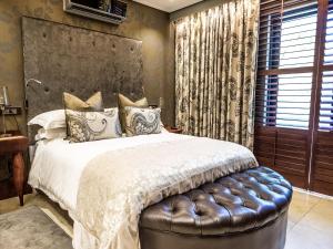 a bedroom with a large bed with a leather seat at Kimberley Anne Hotel in Kimberley