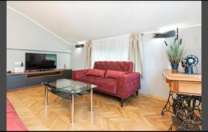 een woonkamer met een rode bank en een glazen tafel bij Apartment Punta with garage, balcony, garden and sea view in Opatija