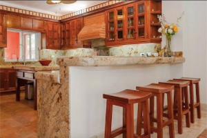 a kitchen with wooden cabinets and bar stools at 5 BD Luxury Villa with Large Pool & Minutes from Beach in Puerto Aventuras