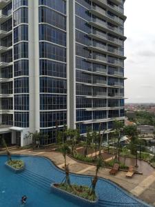 a view of a large building and a swimming pool with palm trees at Signature Apartment @ The Windsor in Jakarta