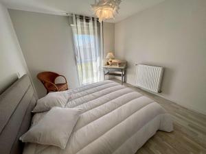 a large white bed in a room with a window at Étel - Appt. moderne 2 pièces, Wifi & parking, à 700m de la plage - FR-1-479-171 in Étel