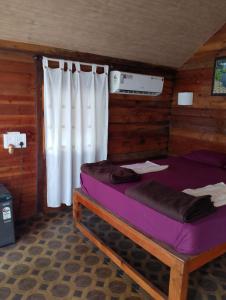 a bed in a wooden room with a window at Lamarine Morjim Beach cottages in Old Goa