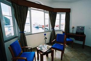 ein Wohnzimmer mit Tisch, Stühlen und Fenstern in der Unterkunft Casa Do Antonio in Velas