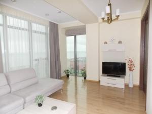 uma sala de estar com um sofá branco e uma televisão em Anna's Sea View Apartment em Batumi