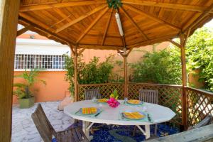 a patio with a table and chairs under a wooden umbrella at Gîte L'adérobade in Le Gosier