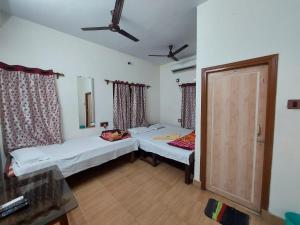 ein Zimmer mit 2 Betten und einer Tür darin in der Unterkunft Rajlaxmi Resort - Pure Veg in Bolpur + 17 Fotos