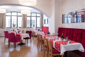 a restaurant with tables and chairs and red booths at Hotel Deutsches Haus in Bonn