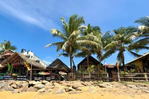 a beach with palm trees and houses on the beach at Malilo Dream in Galle