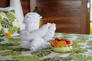 un animal de toallas sentado en una mesa con un tazón de flores en Wooden Stone Eco Villa, en Ubud