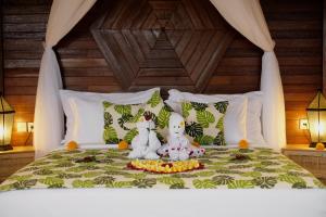 dos animales de peluche sentados encima de una cama en Wooden Stone Eco Villa, en Ubud