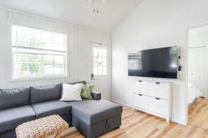 a living room with a couch and a flat screen tv at Lakeside Retreat - Cozy Cottage with Firepit in Hartland