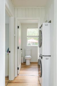 a white bathroom with a toilet and a refrigerator at Lakeside Retreat - Cozy Cottage with Firepit in Hartland +24 photos