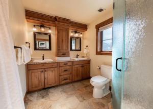 a bathroom with a toilet and two sinks and a mirror at Premium Unit 2801 - Zephyr Mountain Lodge condo in Winter Park