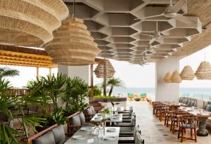 a restaurant with tables and chairs and large ceilings at Hyatt Centric Playa del Carmen - Downtown House & Beach House in Playa del Carmen