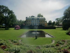 a large house with a pond in the middle of a garden at Wapnö Gårdshotell in Halmstad