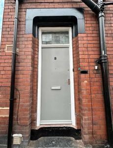 a brick building with a white door and a window at Luxury Studio - Free Parking - Great Location in Leeds