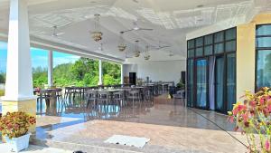 a dining room with tables and chairs and windows at Ocean Cottage 2, Radiant Teluk Sari in Kampung Mawar