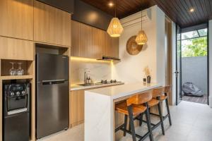 eine Küche mit Kühlschrank und Theke mit Hockern in der Unterkunft Private Villa Ayra 8C by OriVista 10mins to Melasti Beach in Uluwatu
