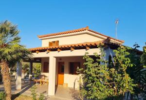a white house with a palm tree in front of it at Iriti's Villa & Dahlia Studio in Platanidia