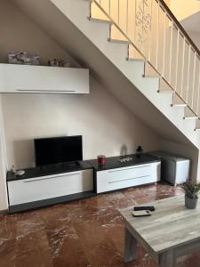a living room with a tv under a staircase at EL NIDO in Montoro