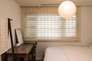 a bedroom with a desk and a window with a lamp at Terastay in Seoul