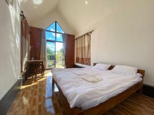 a bedroom with a bed with white sheets and a window at Cool Pool Bungalow in Ban Phônmuang