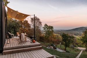 a deck with chairs and an umbrella on a house at Tiny Heart Kabin in Nagymaros