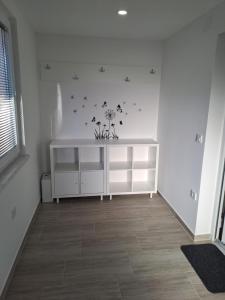 um quarto com uma prateleira branca com flores e borboletas na parede em Apartma Anci em Prosenjakovci
