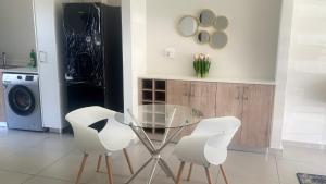 a dining room with a glass table and two white chairs at Mya Villa 2 in Fourways