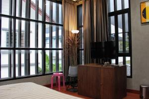 a bedroom with a bed and a tv and large windows at The Melatonin Hostel - Whole Home แบบเหมาหลัง in Hat Yai