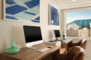 a desk with a computer on it with a window at Surfbreak Virginia Beach Oceanfront, Ascend Hotel Collection in Virginia Beach +19 photos