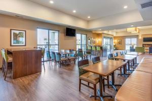 ein Restaurant mit Holztischen, Stühlen und Fenstern in der Unterkunft Comfort Suites Burlington near I-5 in Burlington