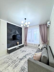 a living room with a couch and a television at INJU апартаменты in Taldykolʼ +13 photos