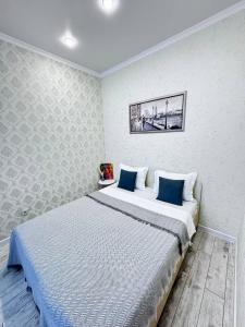a bedroom with a large bed with blue pillows at INJU апартаменты in Taldykolʼ