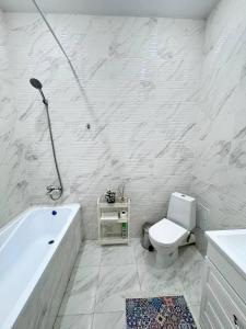 a white bathroom with a tub and a toilet at INJU апартаменты in Taldykolʼ