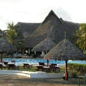 マリンディにあるFlappy Beach Villa Malindi Mambruiのプールサイドのリゾート(椅子、パラソル付)