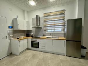 Una cocina con gabinetes blancos y un refrigerador de acero inoxidable. en Suite la Bella, en Torre del Mar 5 fotos más