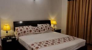 a bedroom with a large bed with two lamps on tables at Hotel Imperial ByHI in Karachi