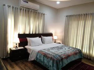 a bedroom with a bed with two lamps and curtains at Hotel Imperial ByHI in Karachi +1 photo