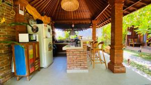an outdoor kitchen with a refrigerator and tables and chairs at Kubu Pering in Keramas