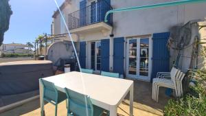 MARINA DEL SOL Aigues Mortes في إج مورت: طاولة بيضاء وكراسي خارج المبنى +صورتان