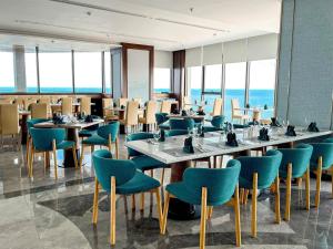 a dining room with tables and chairs and the ocean at Apec Mandala Cham Bay Condotel Mui Ne in Mui Ne