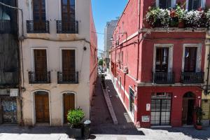 an alley between two buildings with flowers on the balconies at Al Merlo da Diego in Cagliari