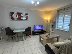 a living room with a couch and a tv and a table at Pôle Thermal & Touristique Amnéville in Amnéville +7 photos