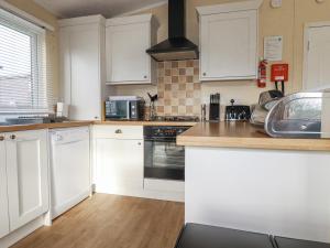 a kitchen with white cabinets and a stove top oven at Laurel Lodge in Tintagel