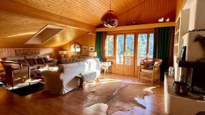 Una sala de estar con muebles blancos y una gran ventana. en Gstaad - Cozy spacious Flat right in the village, en Rougemont