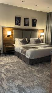 Una cama grande en una habitación de hotel con dos lámparas. en أساليب بلاتينيوم للشقق المخدومة, en Medina