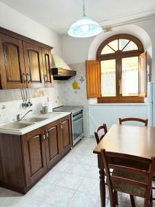 a kitchen with wooden cabinets and a sink and a table at Casa Antonietta - SHARDANAPARTMENTS in Iglesias +54 photos
